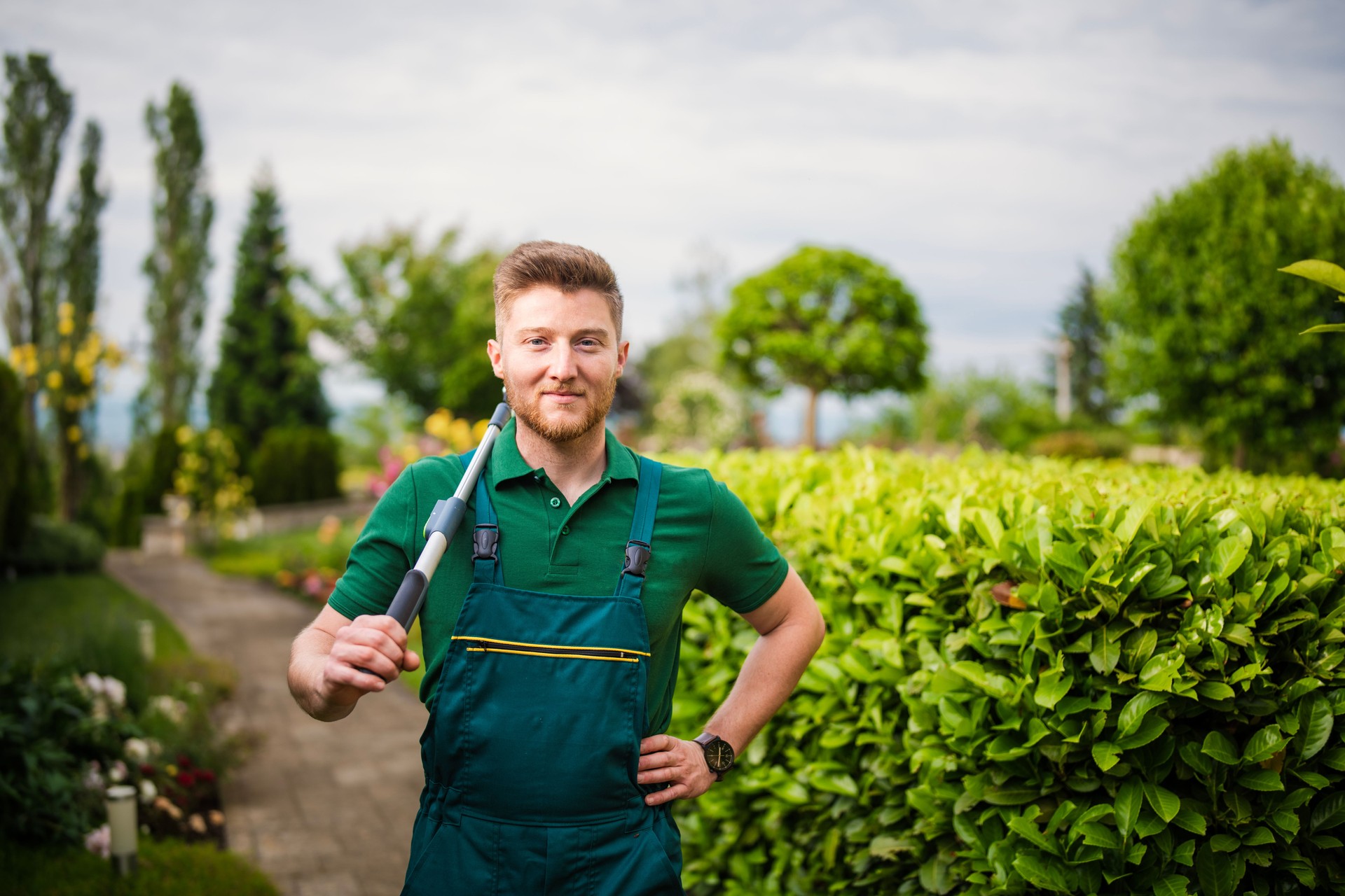 Portrait of a cheerful landscaper at work in a beautiful green garden.