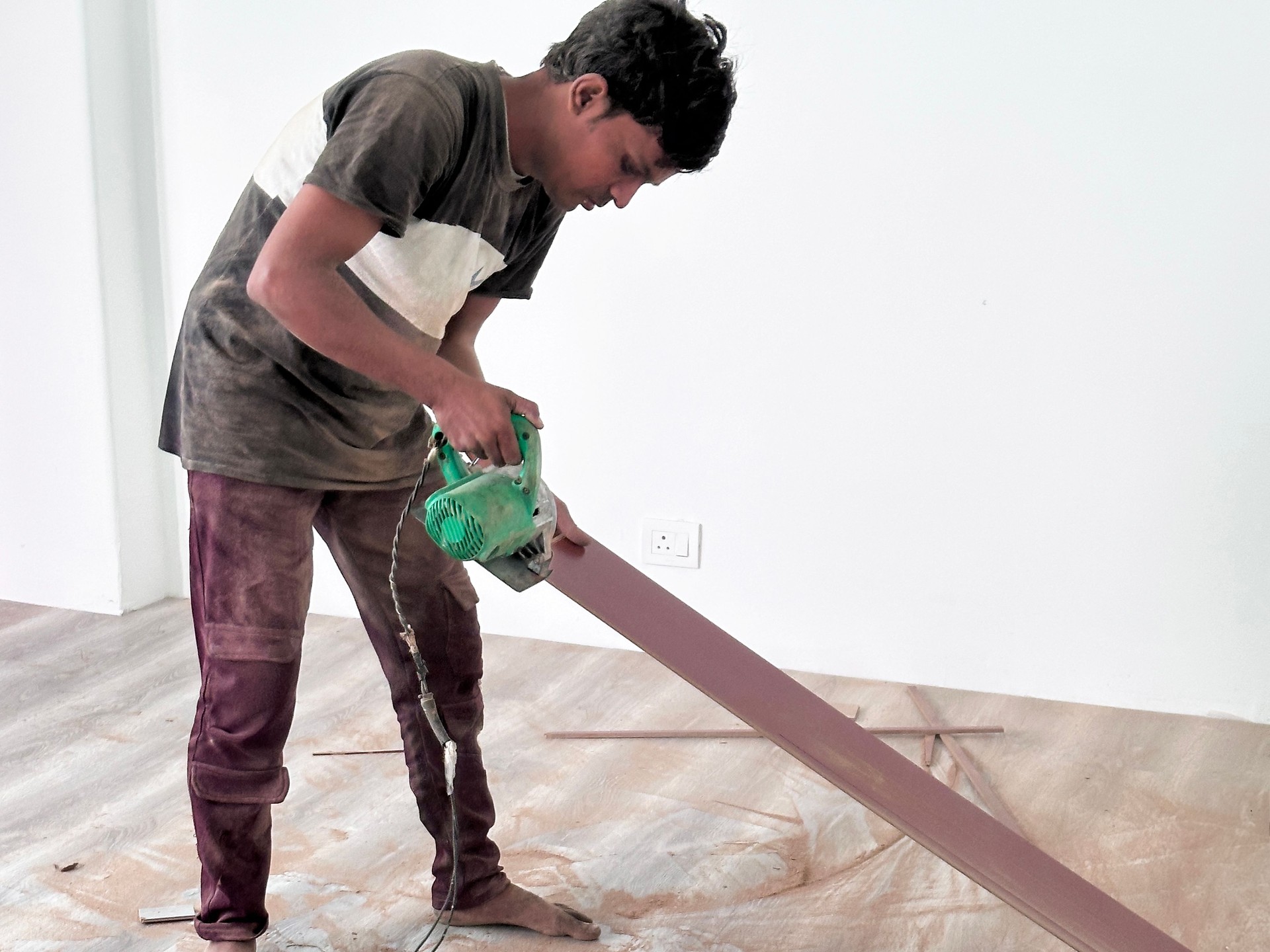 Image of skilled carpenter using electric saw to cut timber, laminate flooring installation /  fitting for wooden floors, professional flooring expert